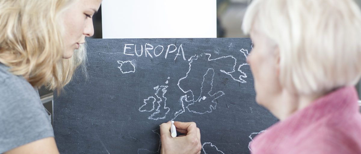 Symbolbild: Frau zeichnet Europakarte mit Kreide auf Tafel