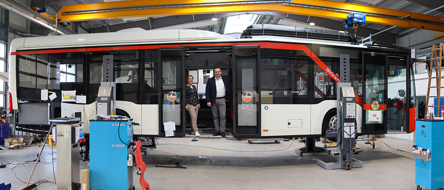 Die Geschäftsführer Leonie Behrens und Philip Wagemann stehen in einem Linienbus, der auf Wasserstoff umgerüstet wird. 