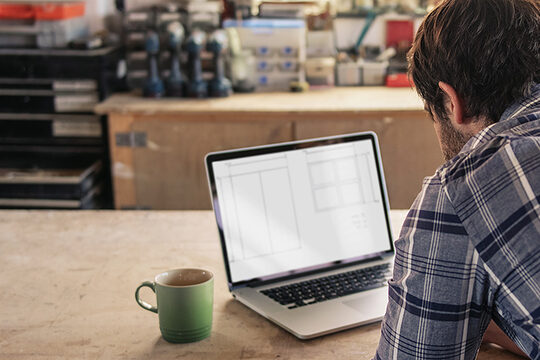 Ein Handwerker arbeitet an seinem Laptop in der Werkstatt