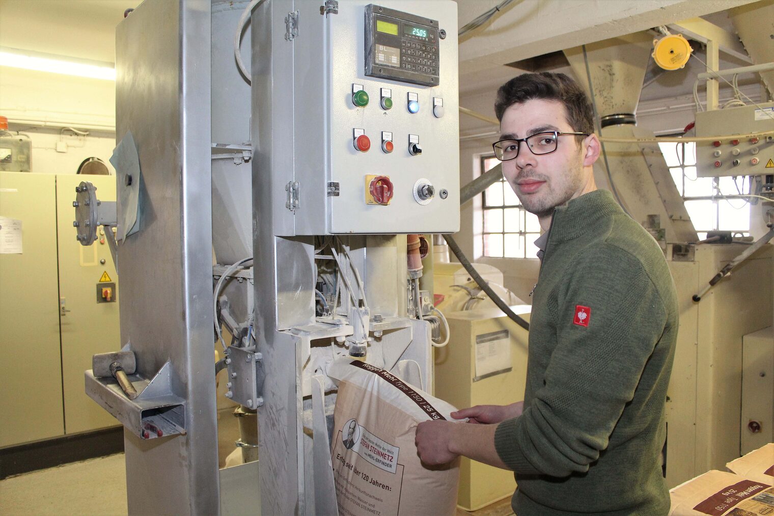 Müllermeister Jonas Engel an einer Absackmaschine zum Auffüllen derMehlsäcke.