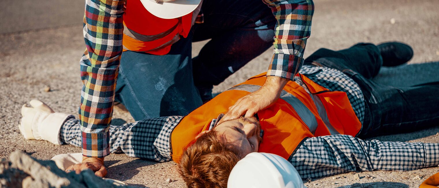 Symbolfoto: Ein Handwerker hilft einem anderen bewusstlosen Handwerker