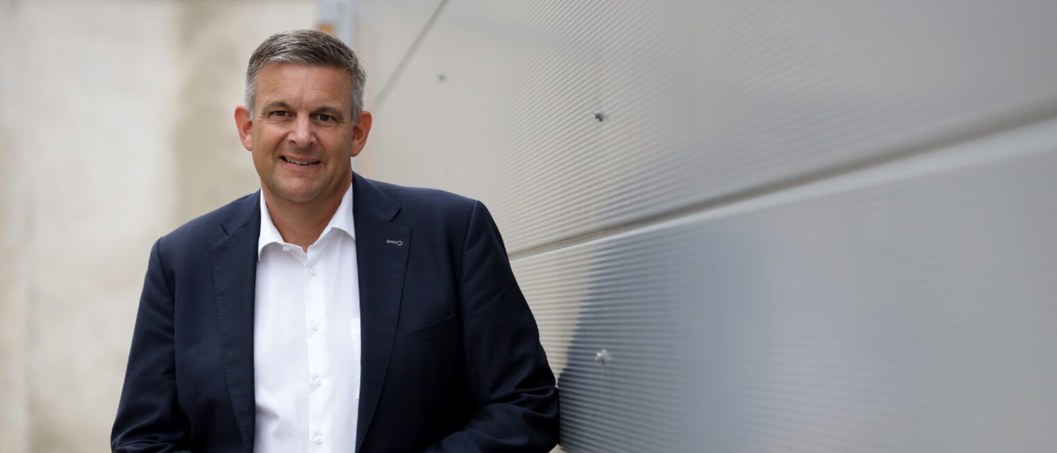 Matthias Steffen, Hauptgeschäftsführer der Handwerkskammer, im Anzug vor moderner Wand stehend und freundlich blickend.