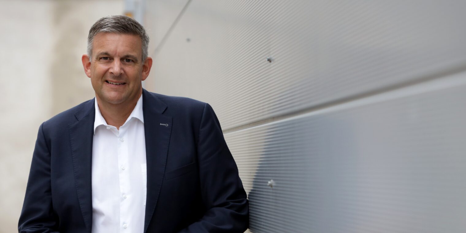 Matthias Steffen, Hauptgeschäftsführer der Handwerkskammer, im Anzug vor moderner Wand stehend und freundlich blickend.