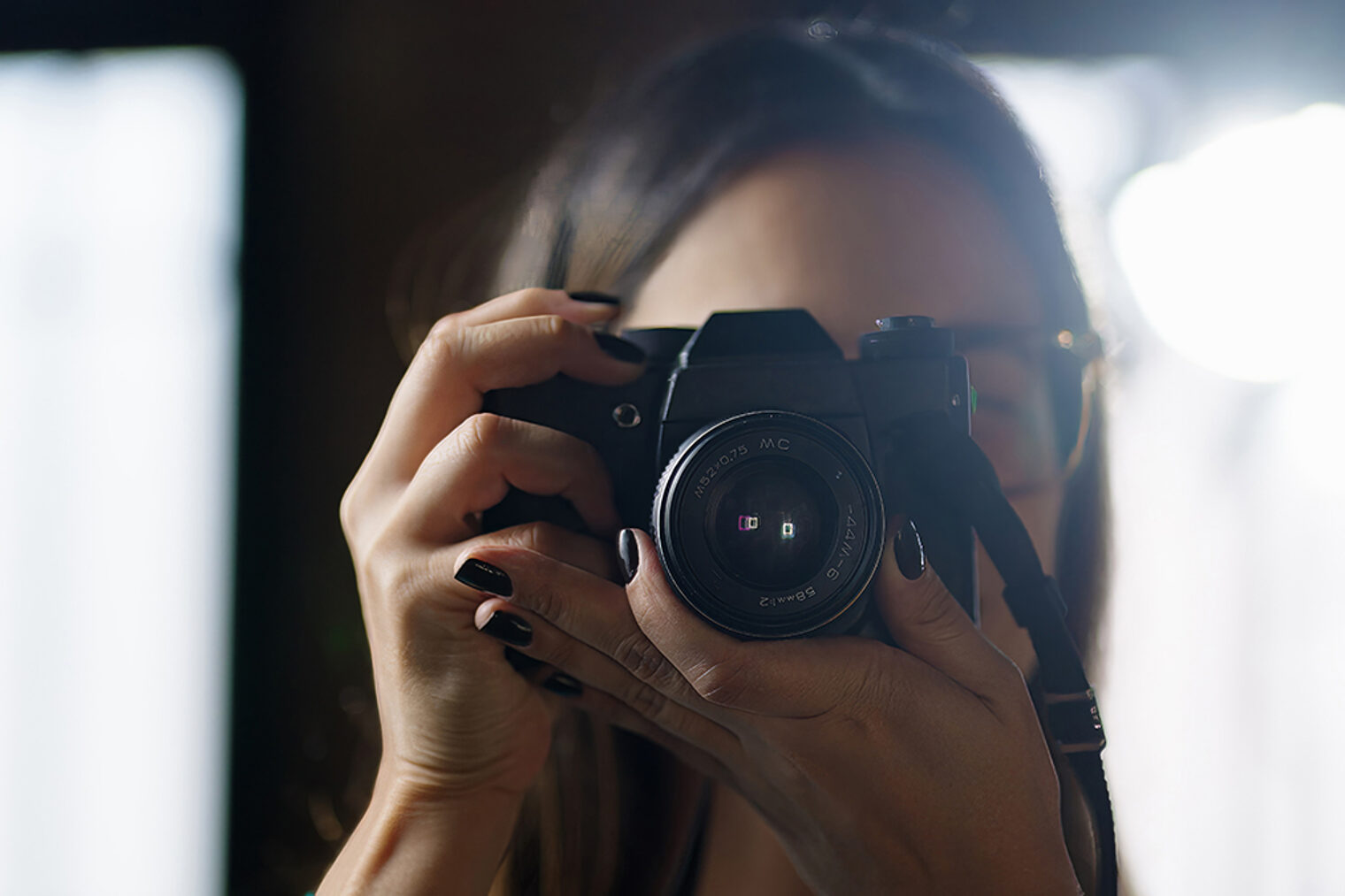 Frau mit dunklem Nagellack fotografiert mit Spiegelreflexkamera im Gegenlicht