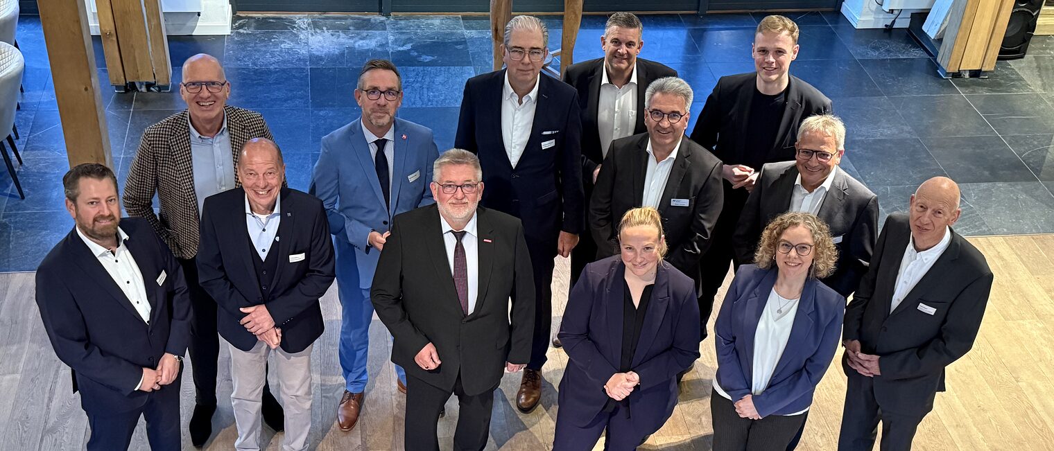 Gruppenfoto von Teilnehmer:innen des Parlamentarischen Abends der Wirtschaft 2025 in Businesskleidung vor moderner Kulisse