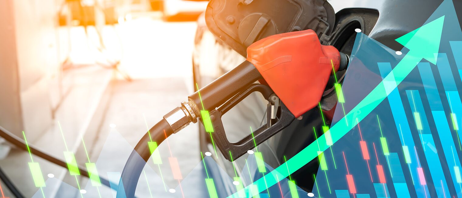 Rote Zapfpistole beim Betanken eines Autos, überlagert von Börsengrafiken und einem steil ansteigenden Pfeil als Symbol für steigende Spritpreise und Kostenbelastungen.