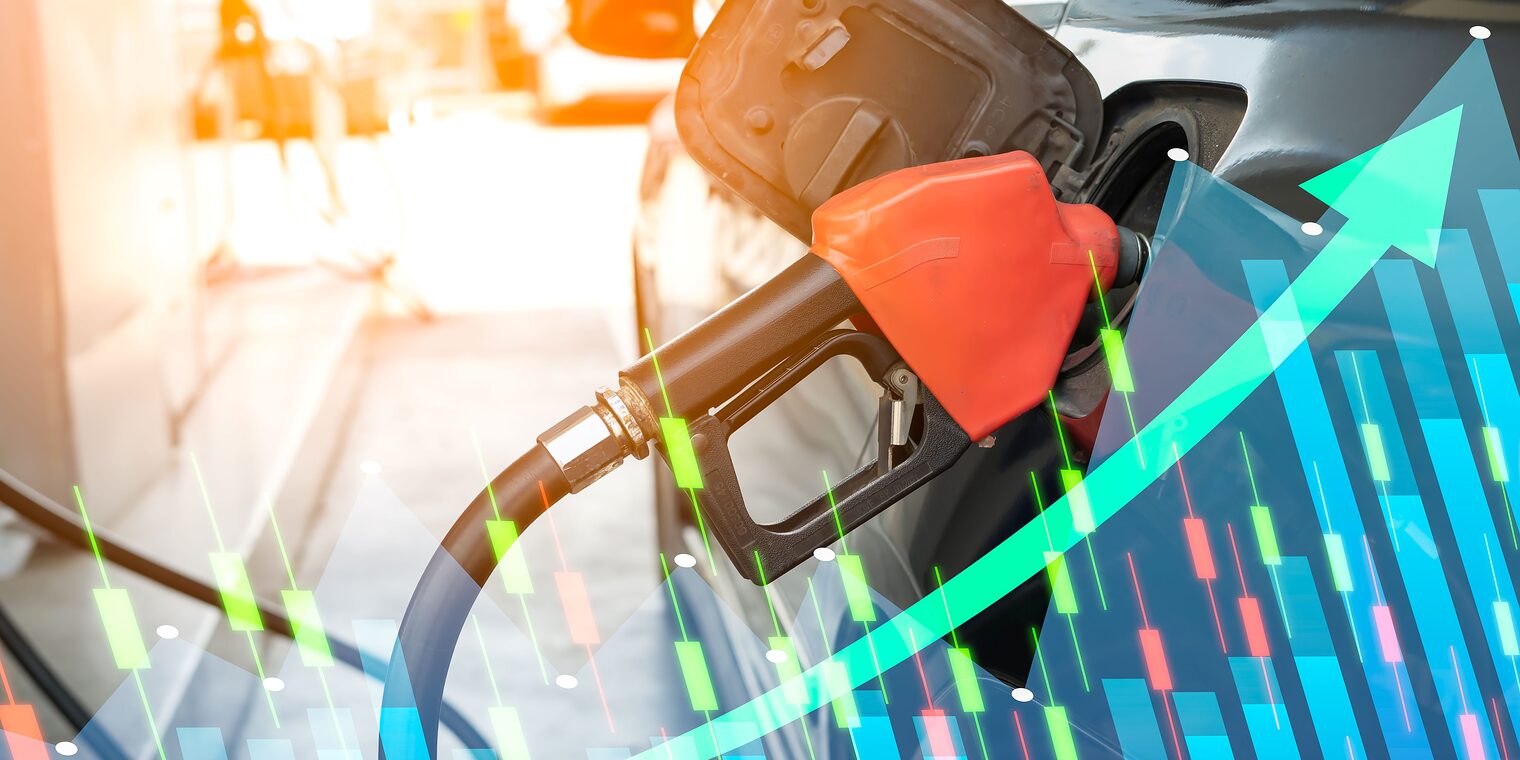 Rote Zapfpistole beim Betanken eines Autos, überlagert von Börsengrafiken und einem steil ansteigenden Pfeil als Symbol für steigende Spritpreise und Kostenbelastungen.
